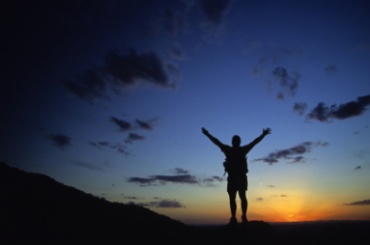 Man lifting his arms to the twilight sky