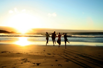 Four people running and skipping on the beach